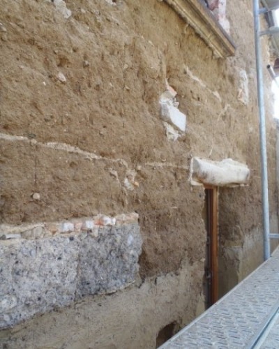 Façade terre-paille-chaux-sable entièrement enduite.